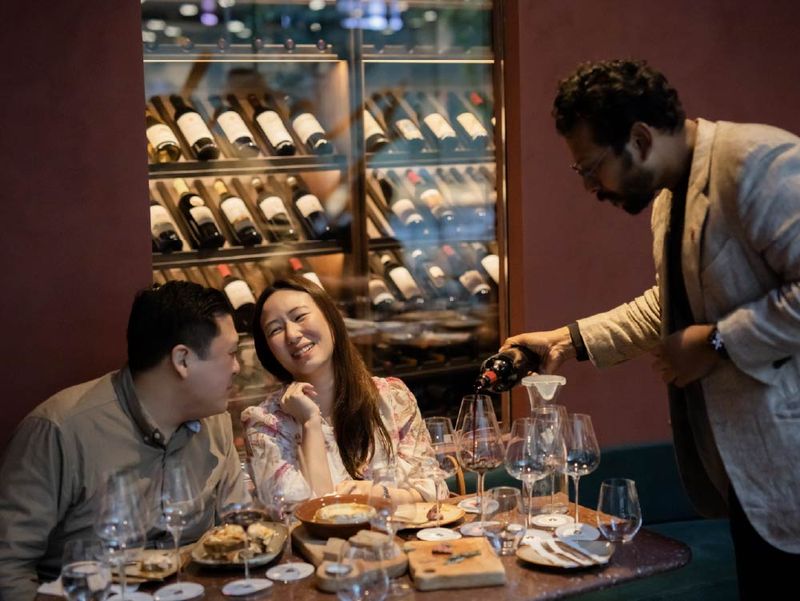 Two members sharing a laugh as wine is poured at a VANTA tasting