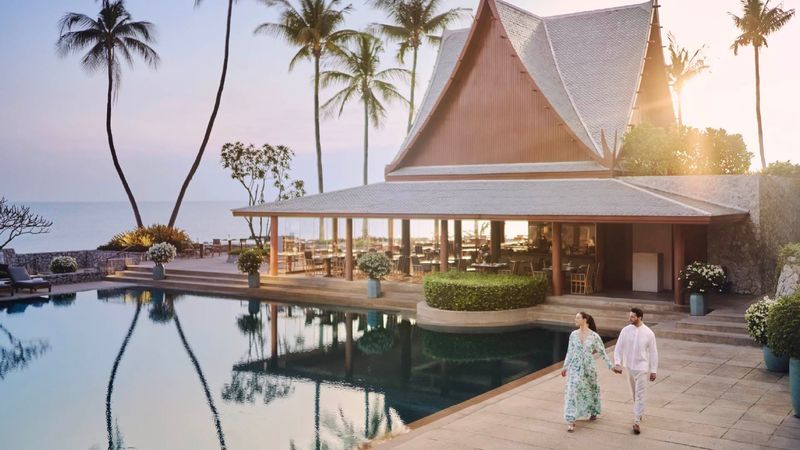 Guests walking beside the pool of a beachfront resort pavilion at sunset, one of the VANTA partner properties